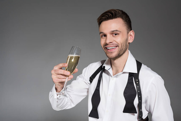 handsome smiling man holding glass of champagne isolated on grey - Foto, immagini
