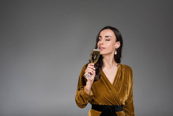 beautiful dreamy woman drinking champagne with closed eyes isolated on grey - Fotó, kép
