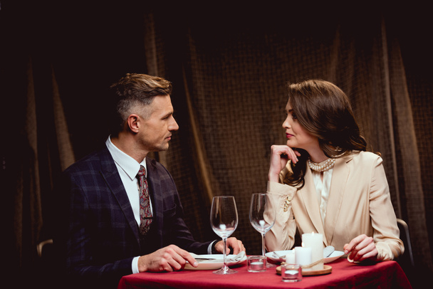 beautiful couple sitting at table and looking at each other during romantic dinner in restaurant - 写真・画像