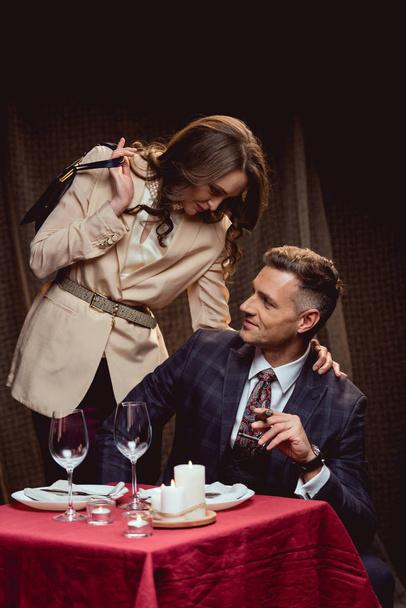 mulher abraçando o homem sorridente com charuto durante o jantar romântico no restaurante
 - Foto, Imagem
