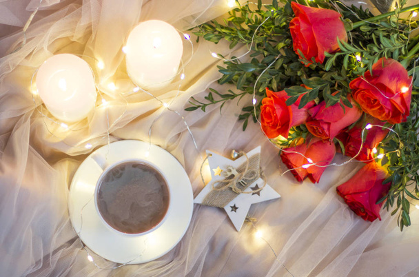 Σύνθεση από κόκκινα τριαντάφυλλα με το πυξάρι και στεφάνια με κεριά και φλιτζάνι καφέ  - Φωτογραφία, εικόνα