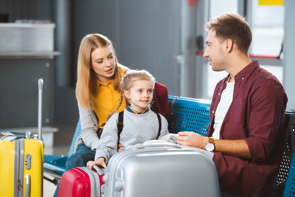 attractive mother talking with daughter near suitcases and husband in departure lounge - Foto, Imagen