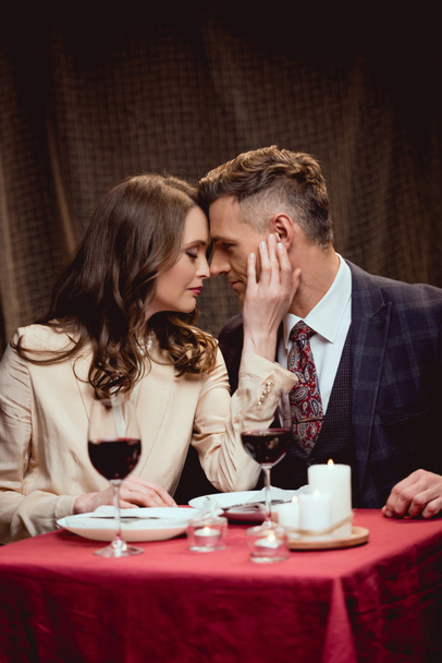 Kobieta, delikatnie dotykając twarz człowieka podczas romantyczną randkę w restauracji - Zdjęcie, obraz