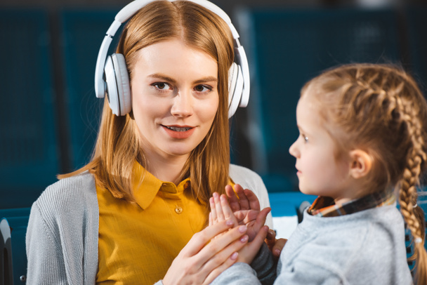 enfoque selectivo de la atractiva madre escuchando música en auriculares cerca de la hija
  - Foto, Imagen