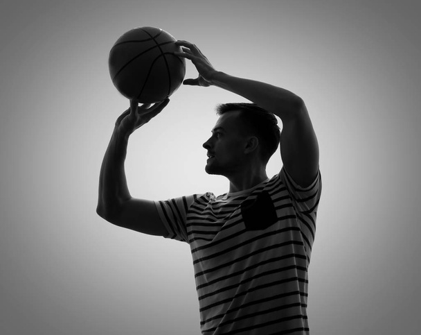 Силует молодого чоловіка, який грає в баскетбол на сірому фоні
 - Фото, зображення