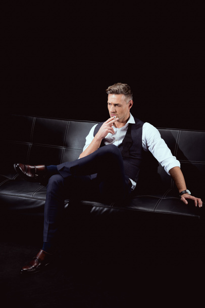 súlyos jóképű férfi, a fotelben ülve, cigaretta, elszigetelt fekete hivatalos viselet - Fotó, kép