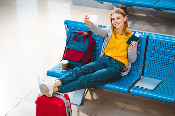 Lachende vrouw nemen selfie in vliegveld in de buurt van de rugzak en Bagage - Foto, afbeelding