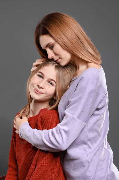 Portrait of happy mother and daughter on grey background - Photo, Image