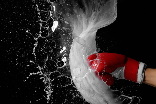 Hand in boxing glove with splashes of liquid on dark background - Фото, изображение