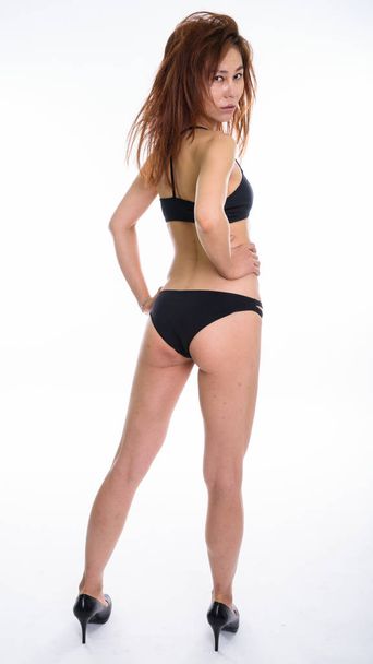 Full body shot of young Asian woman looking back while posing an - Foto, Bild