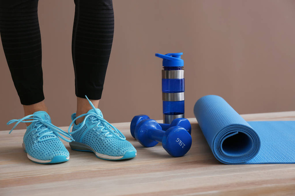 Młoda kobieta sportowy z maty do jogi, butelkę wody i hantle w siłowni - Zdjęcie, obraz