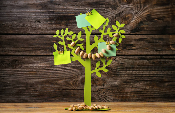 Decorative tree with pistachio garland on wooden background - Foto, imagen