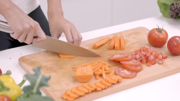 Heureuse femme asiatique couper beaucoup de carotte préparer ingrédient pour faire des aliments dans la cuisine, utilisation féminine de légumes biologiques pour des aliments sains à la maison. Mode de vie femmes faisant concept alimentaire
. - Séquence, vidéo