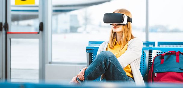 vrouw die virtual reality headset draagt zittend in luchthaven - Foto, afbeelding