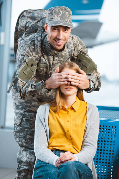 handsome veteran in military uniform closing eyes of girlfriend  - Fotografie, Obrázek
