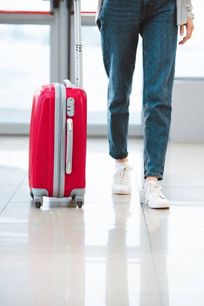cropped view of woman walking with suitcase in airport  - Foto, Imagen