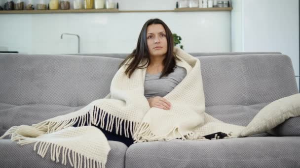 A woman is watching TV with a blanket - Filmati, video