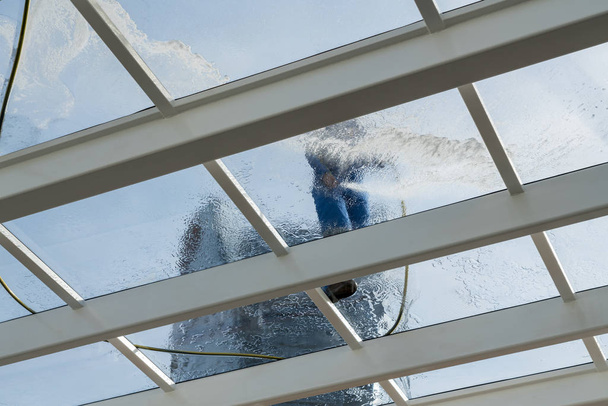 Pracownik do czyszczenia dużym szklanym dachem nad basenem - Zdjęcie, obraz