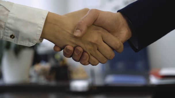 Closeup of handshake on background of office. Good business deal secured partnership with handshake. Two coworkers handshaking process - Photo, Image