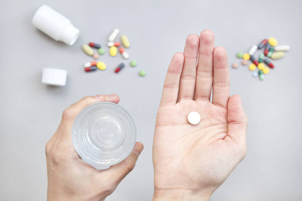 white pill and a glass of water in man hands. health concept - Photo, Image