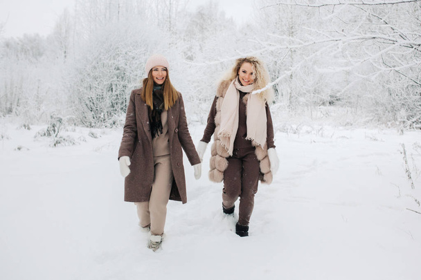 Portrait of two blonde women in hat on walk in winter forest - 写真・画像
