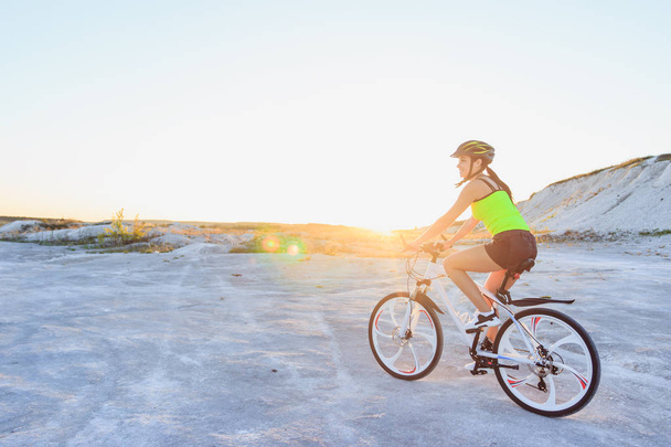 Mulher bonita nova com uma bicicleta do esporte em um fundo azul do céu
 - Foto, Imagem