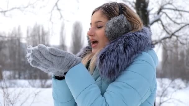 krásná mladá žena držící sníh v dlaních a foukala na ni - Záběry, video