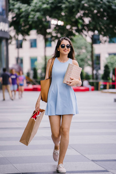 young, fashionable and happy young Indian Asian woman in a blue dress walking down a street in the shopping district  - Foto, imagen