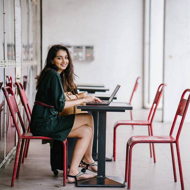 young university student (Indian Asian woman) is studying and working on her laptop computer at a table during the day - Foto, Imagem