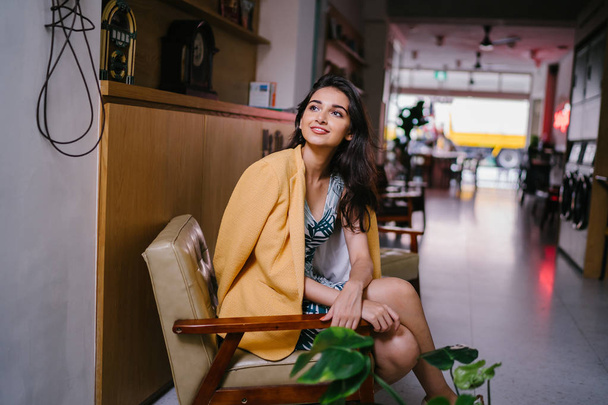 Fashionable, elegant and young Indian Asian woman in a retro outfit. She is wearing a yellow jacket draped over a comfortable summer outfit. - Foto, afbeelding