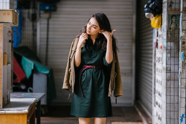 young, tall, slim and elegant Indian Asian woman poses for a portrait. She is wearing comfortable and stylish casual clothing and has a man's jacket draped over her shoulders.  - Foto, Imagem