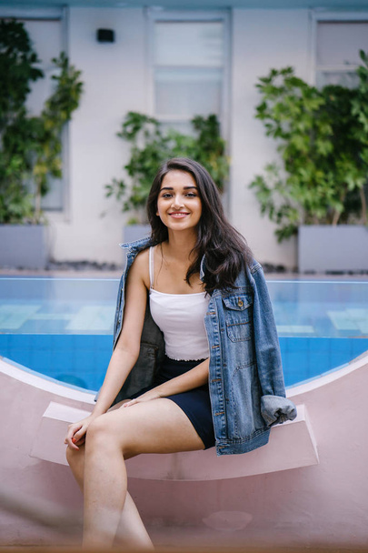 Portrait of a beautiful, young and attractive Indian Asian woman in a white top, blue skirt and denim jacket. - Zdjęcie, obraz