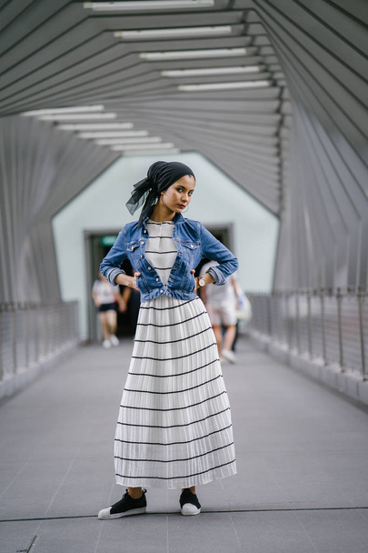 Young, elegant and attractive Malay Muslim woman wearing dress and denim jacket during the day. - Foto, afbeelding