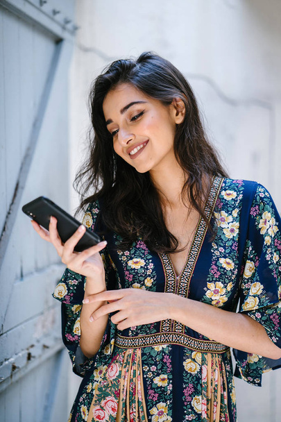 Portrait of a young, attractive and beautiful Indian Asian woman wearing a dress and sunglasses with her smartphone - Fotografie, Obrázek