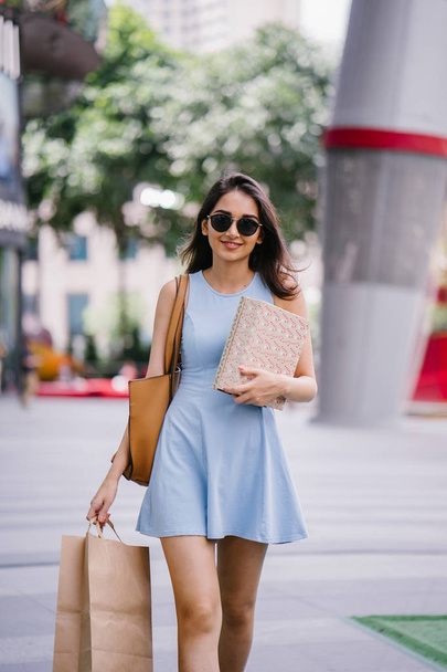 young, fashionable and happy young Indian Asian woman in a blue dress walking down a street in the shopping district  - Zdjęcie, obraz