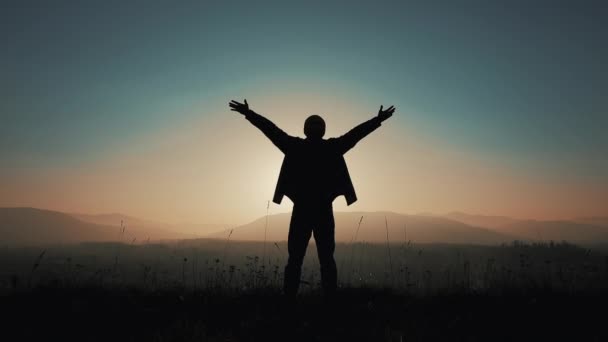 Sylwetka człowieka podnosi ręce stojący na górskich na zachód słońca. Pojęcie wolności - Materiał filmowy, wideo