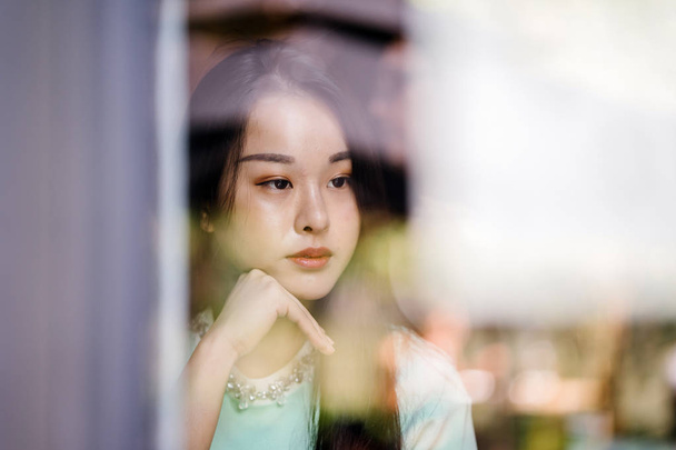 Portrait of a young, sexy and glamorous Asian woman during the day. She is wearing a mint green sweater - Fotoğraf, Görsel
