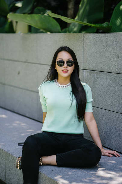 Portret van een jonge, sexy en glamoureuze Aziatische vrouw overdag. Ze draagt een mintgroene trui. - Foto, afbeelding