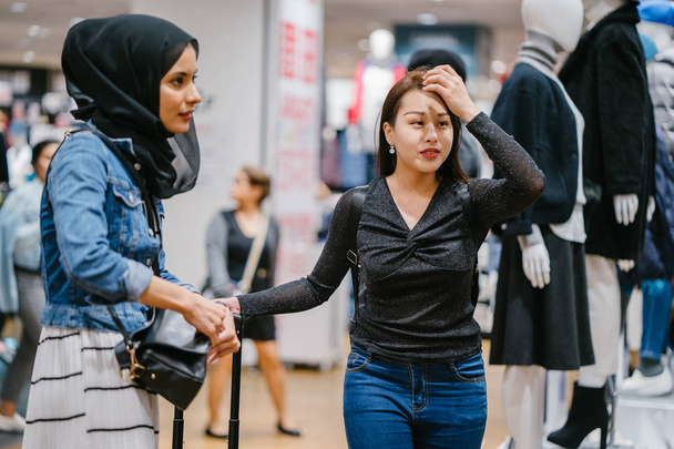 two female friends in shopping mall, one of them Chinese and other is Muslim - Фото, зображення