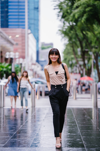 young Chinese Asian woman standing outside a mall in Asia with shopping malls in the background - Foto, afbeelding