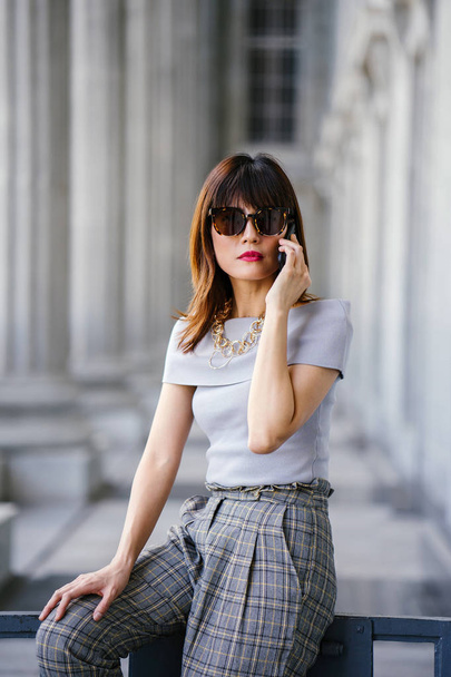 Portrait of an attractive, confident and successful Chinese Asian woman. She is talking on her smartphone  - Foto, Imagem