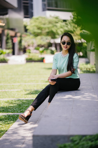 Portrait of a young, sexy and glamorous Asian woman during the day. She is wearing a mint green sweater - Fotó, kép