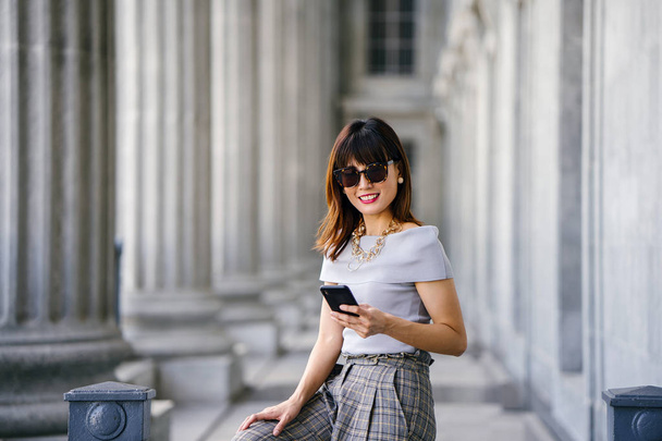 Portrait of an attractive, confident and successful Chinese Asian woman. She is holding her smartphone  - Foto, immagini