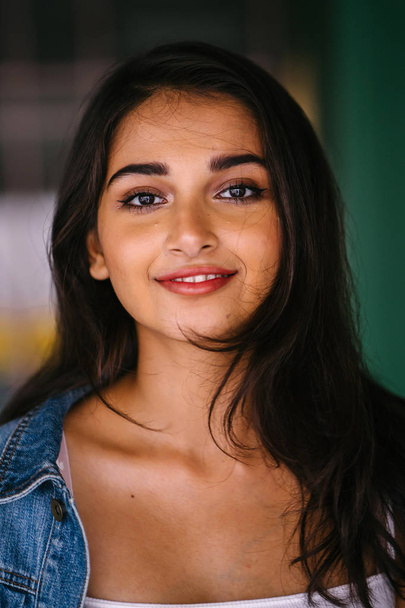 portrait of young and elegant Indian Asian woman in the city during the day. She is wearing a retro denim jacket - Zdjęcie, obraz