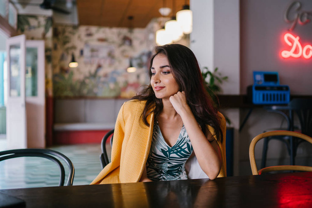 Fashionable, elegant and young Indian Asian woman in a retro outfit. She is wearing a yellow jacket draped over a comfortable summer outfit. - 写真・画像