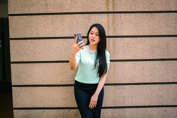 Portrait of a young and beautiful Asian Chinese woman holding smartphone - Fotografie, Obrázek