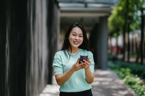 Portrait of a young and beautiful Asian Chinese woman holding smartphone - Fotó, kép