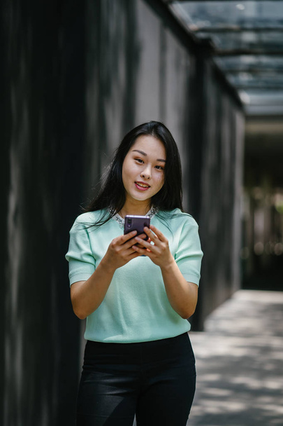 Portrait of a young and beautiful Asian Chinese woman holding smartphone - Фото, изображение