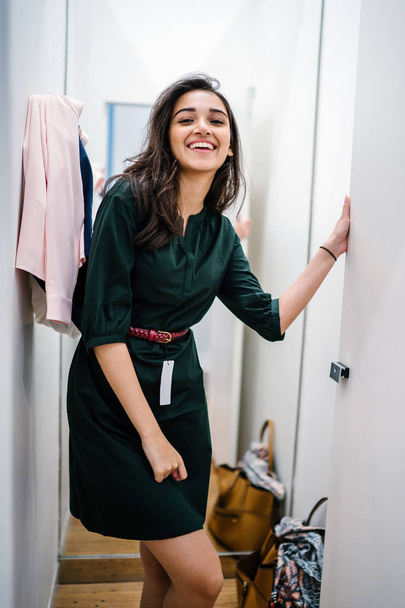 Portrait of a young and beautiful Indian Asian woman trying out new clothing in a fitting room in a fashion shop in a mall. - Foto, Imagen
