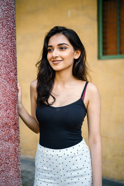 portrait of a young, attractive and beautiful Indian Asian girl in fitting black top - Фото, изображение